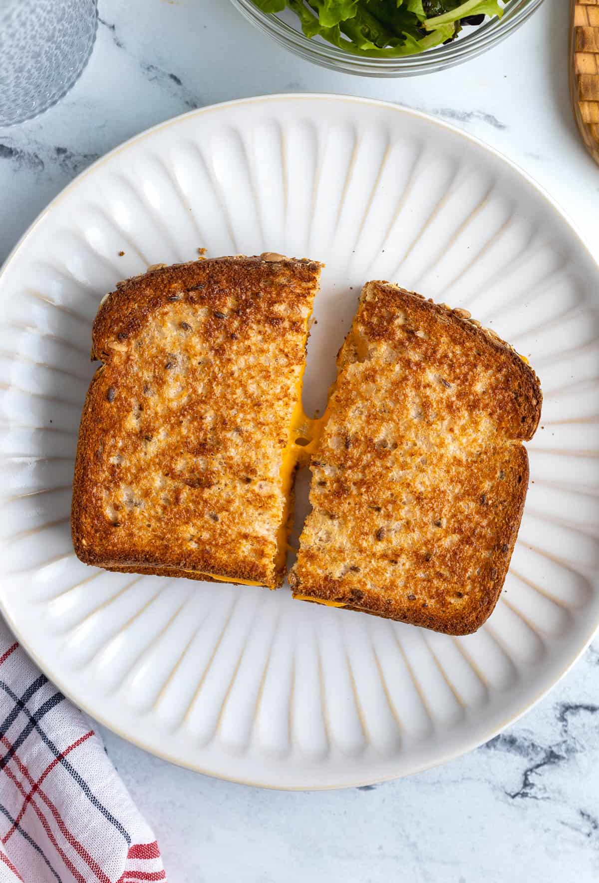 A grilled cheese cut in half with cheese stretching between the halves.