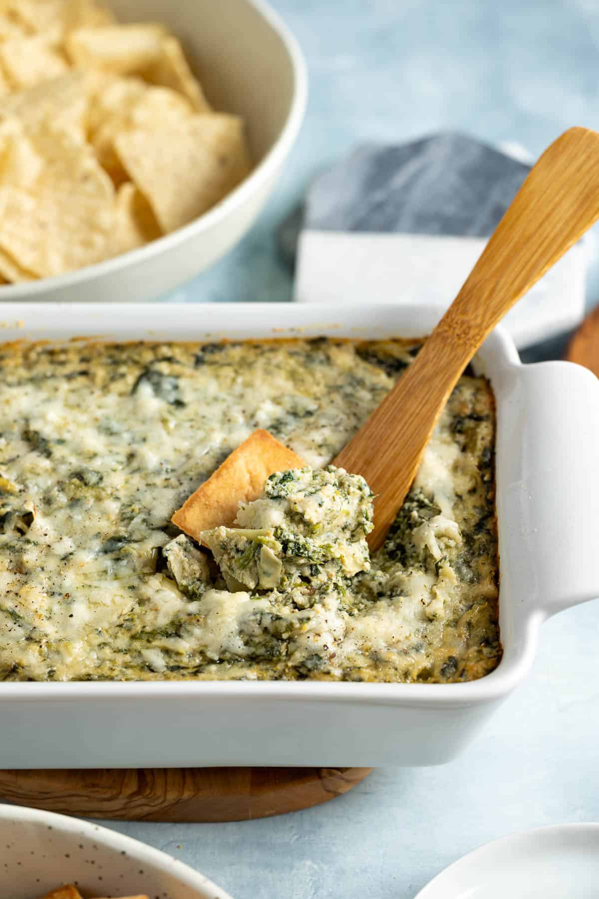 Spinach artichoke dip being scooped out of the serving dish.