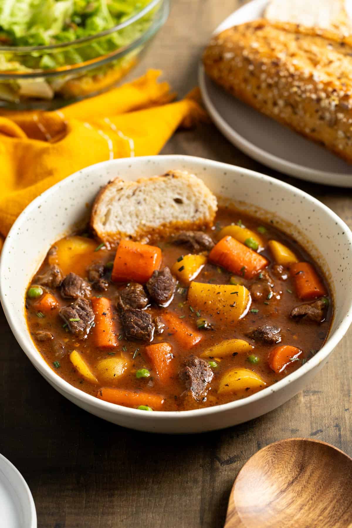 A shallow bowl of Guinness beef stew with a piece of bread dunked in.