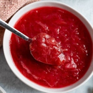 A spoon of stewed rhubarb lifting up out of a serving bowl.