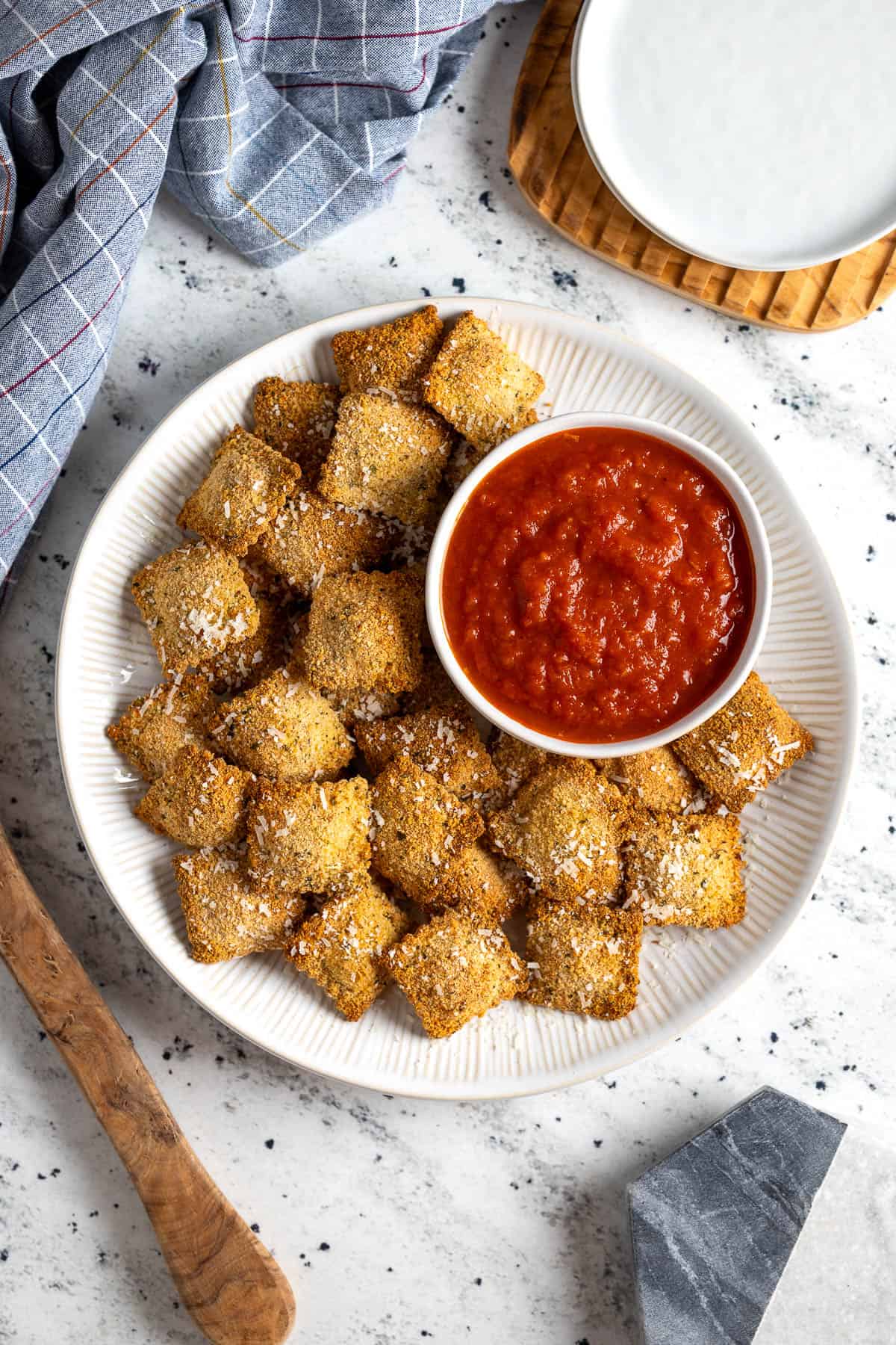 A platter of toasted ravioli with a bowl of marinara sauce.