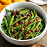 A serving bowl of green beans, bacon, and onions.