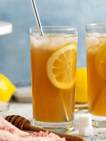 Two limoncello iced teas with straws and lemon rounds in highball glasses.