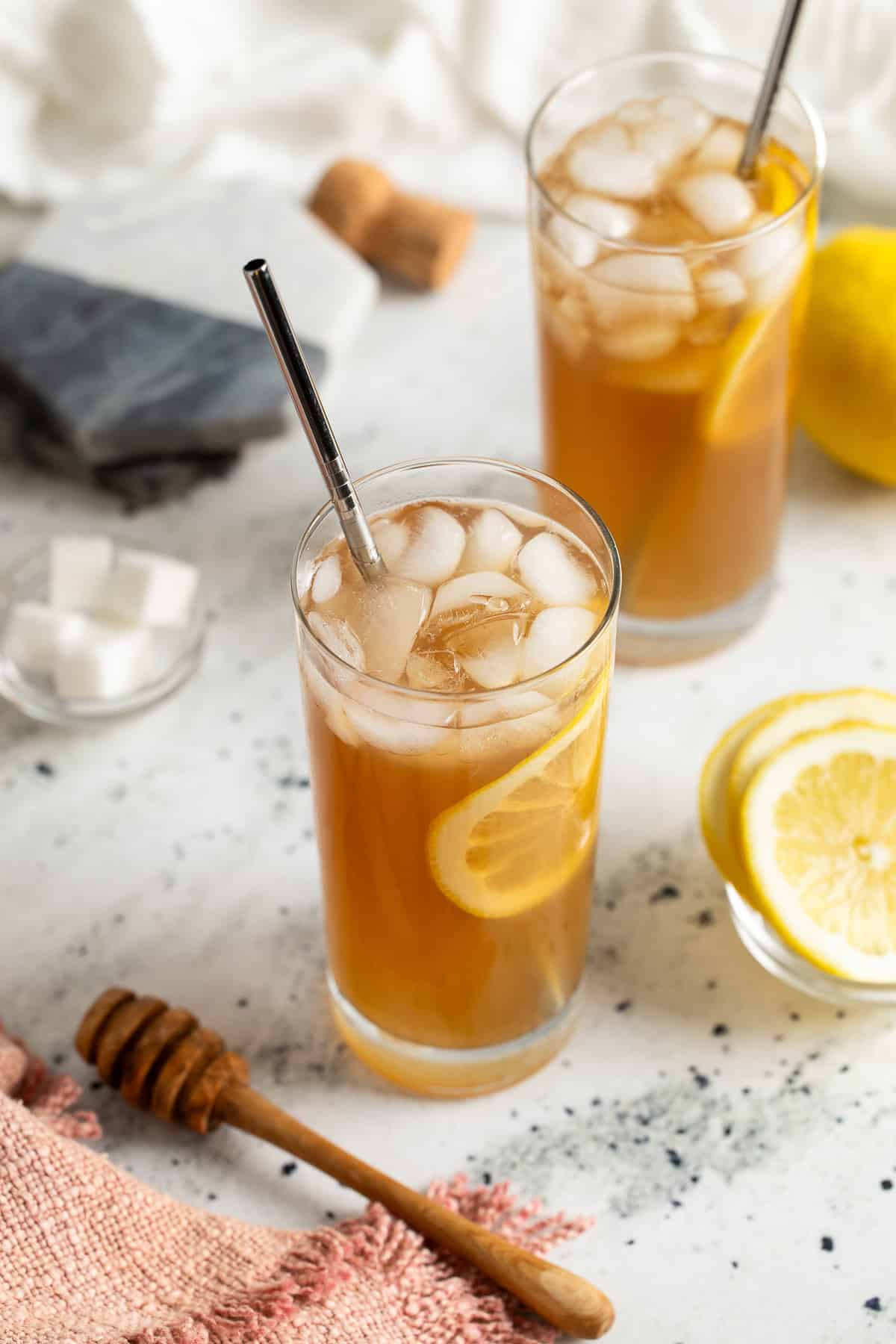Two glasses of limoncello iced tea with metal straws in them.