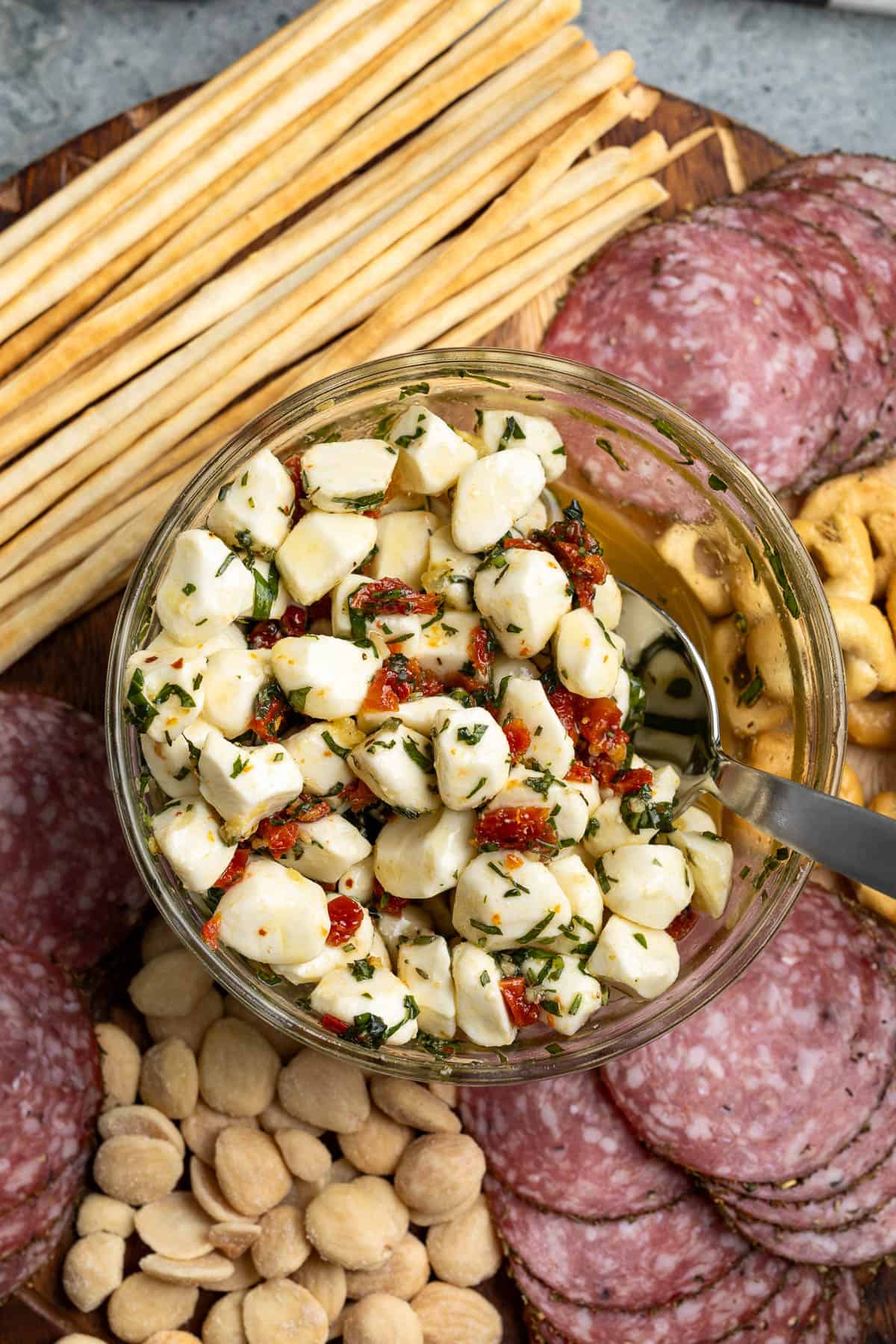 An antipasto platter including marinated mozzarella balls, cured meats, almonds and crackers.