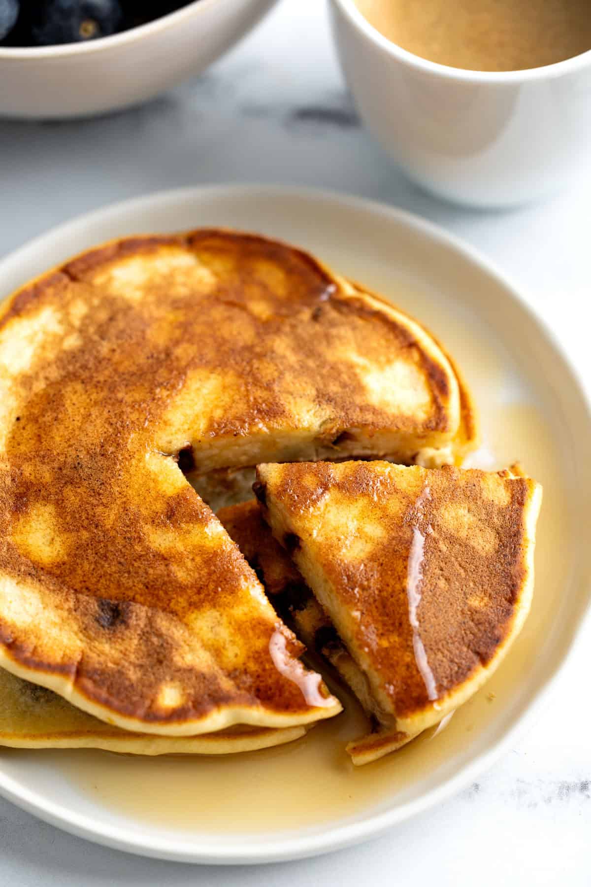 Orange chocolate chip ricotta pancakes on a plate with maple syrup.