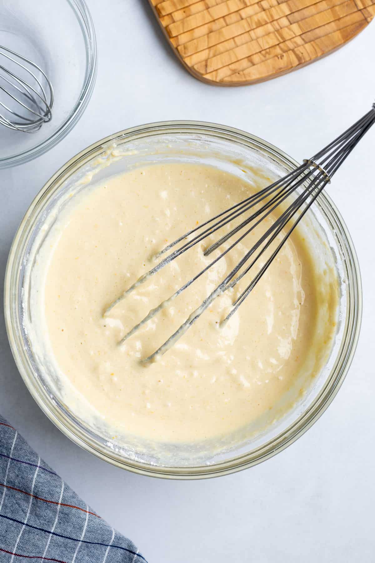 The pancake batter all mixed together in a glass bowl with a whisk in it.