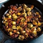 Brussels sprouts and fried bacon in a skillet roasted in a maple syrup and vinegar mixture.