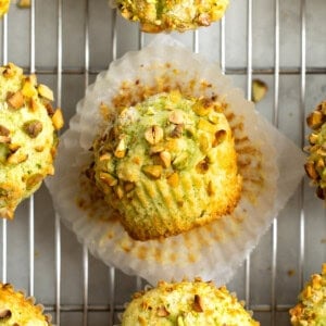 Muffins on a cooling rack with the center one unpeeled from the paper.