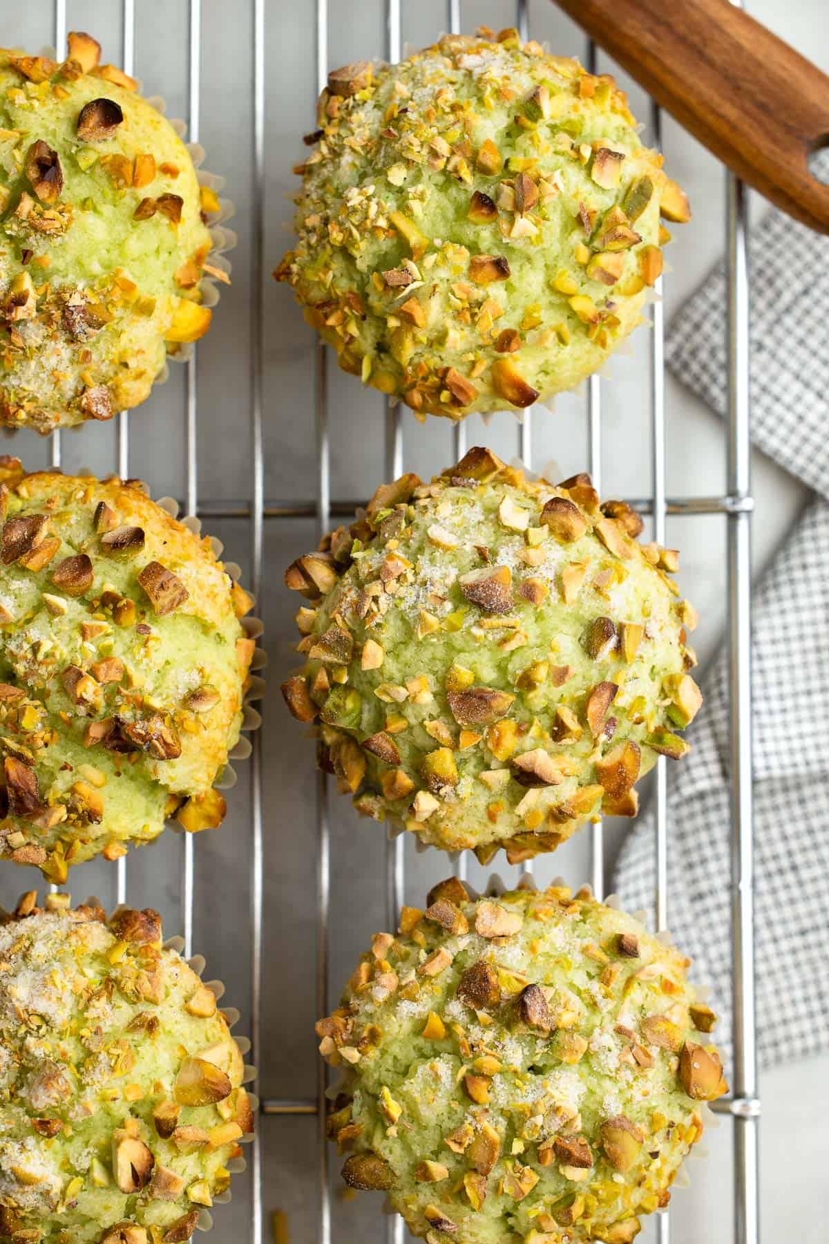 Pistachio muffins on a wire cooling rack.