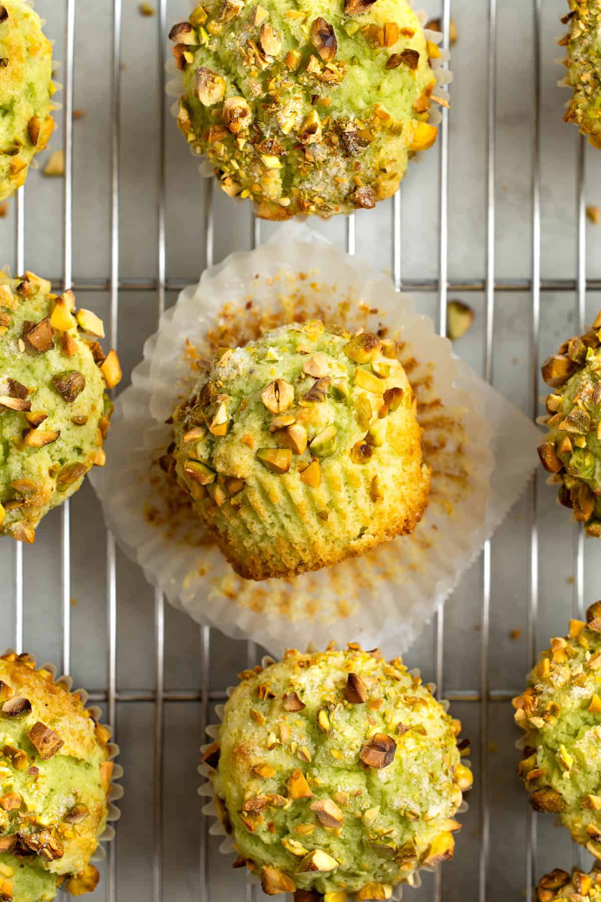 Muffins on a cooling rack with the center one unpeeled from the paper.