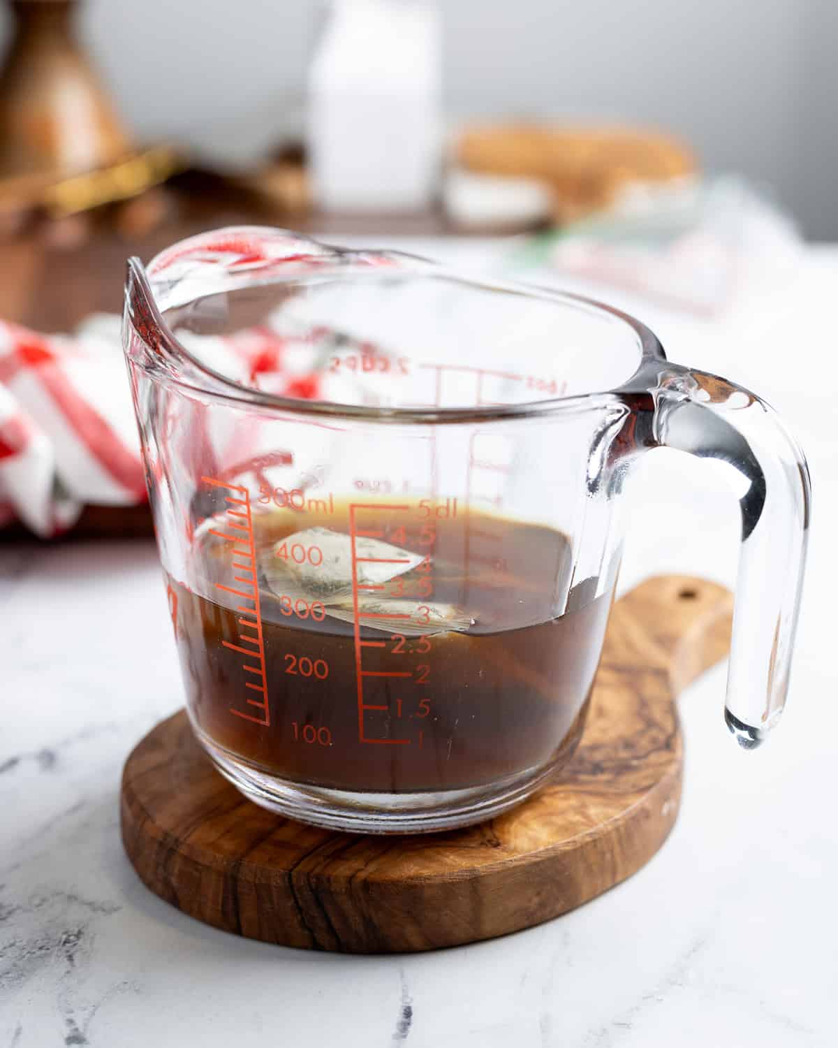 Two peppermint tea bags steeping in a liquid measuring cup of boiling water.