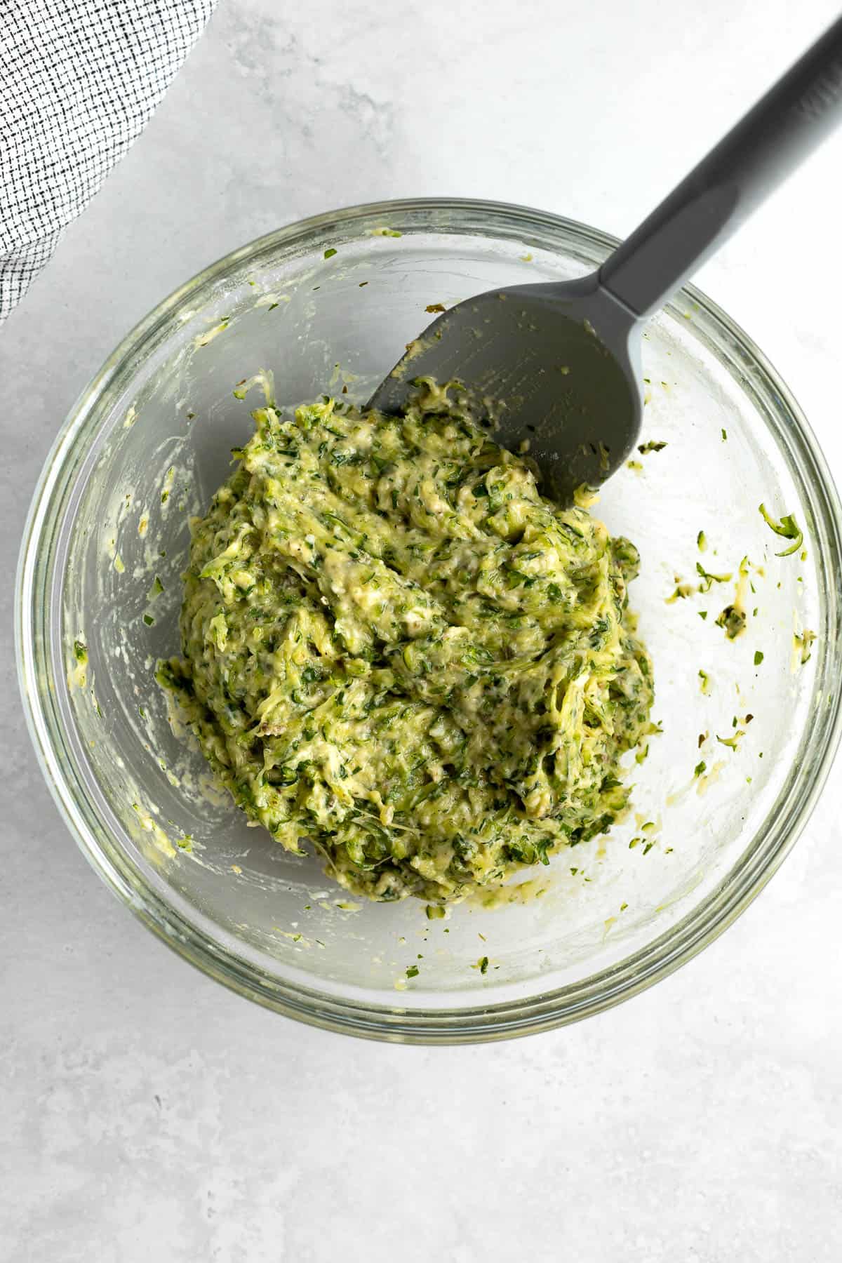 The fritter batter mixed together in a bowl with a spatula.