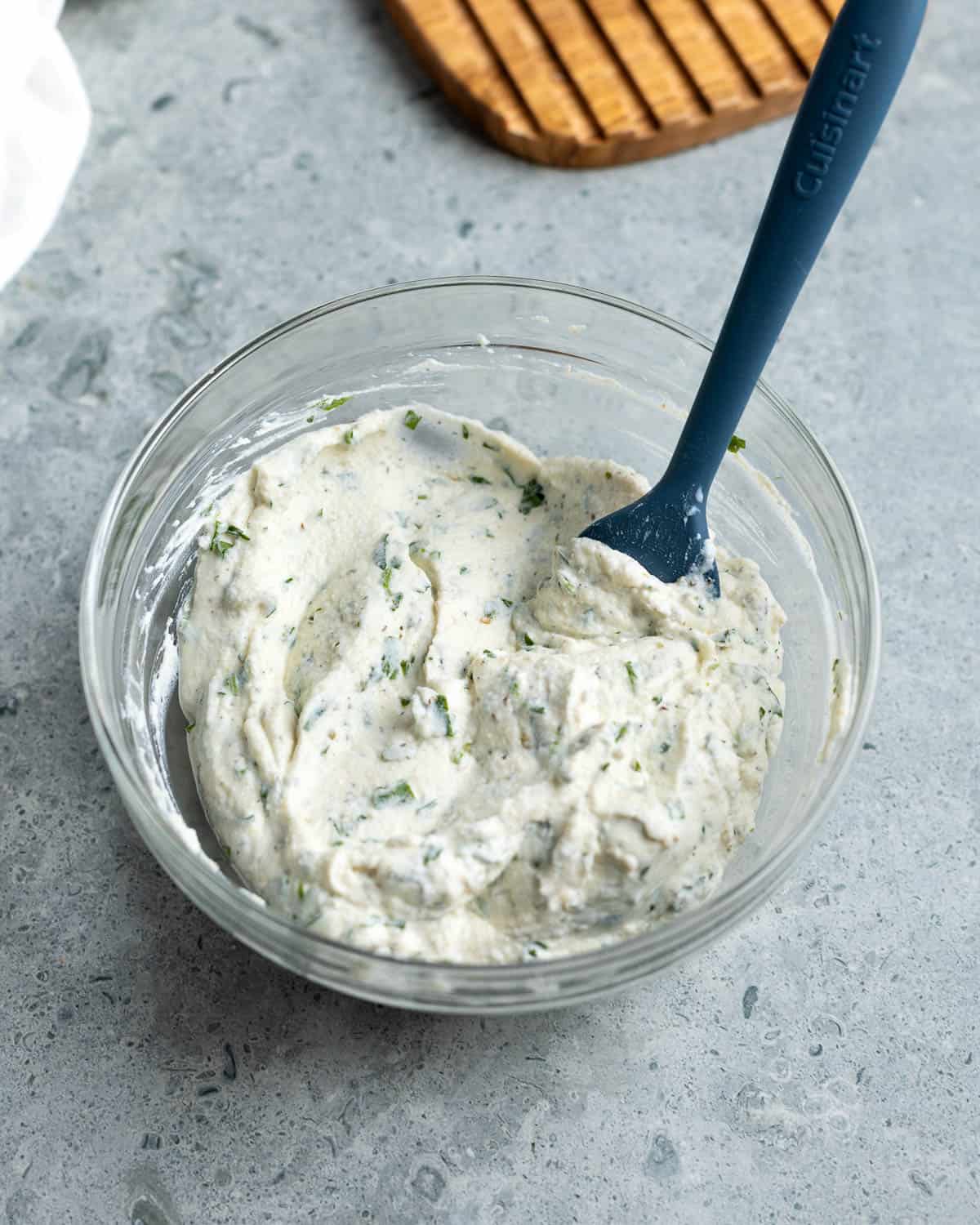 All of the seasonings mixed into the ricotta cheese in a bowl.