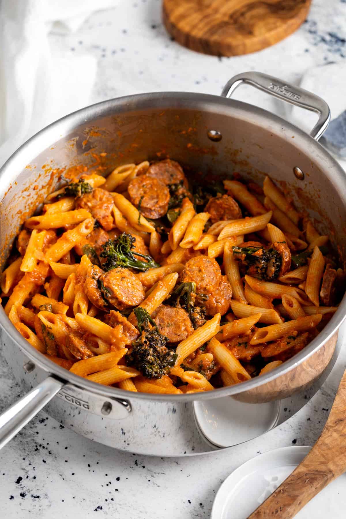 A pan of penne, chicken sausage rounds, and broccolini in creamy marinara sauce.