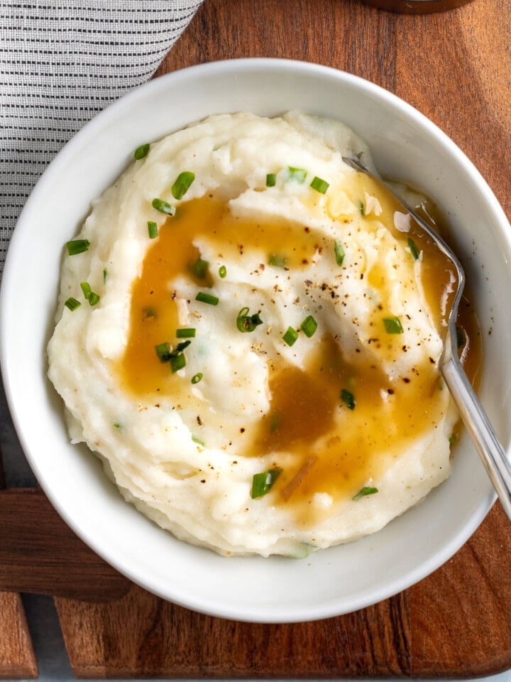 A small bowl of mashed potatoes topped with gravy.