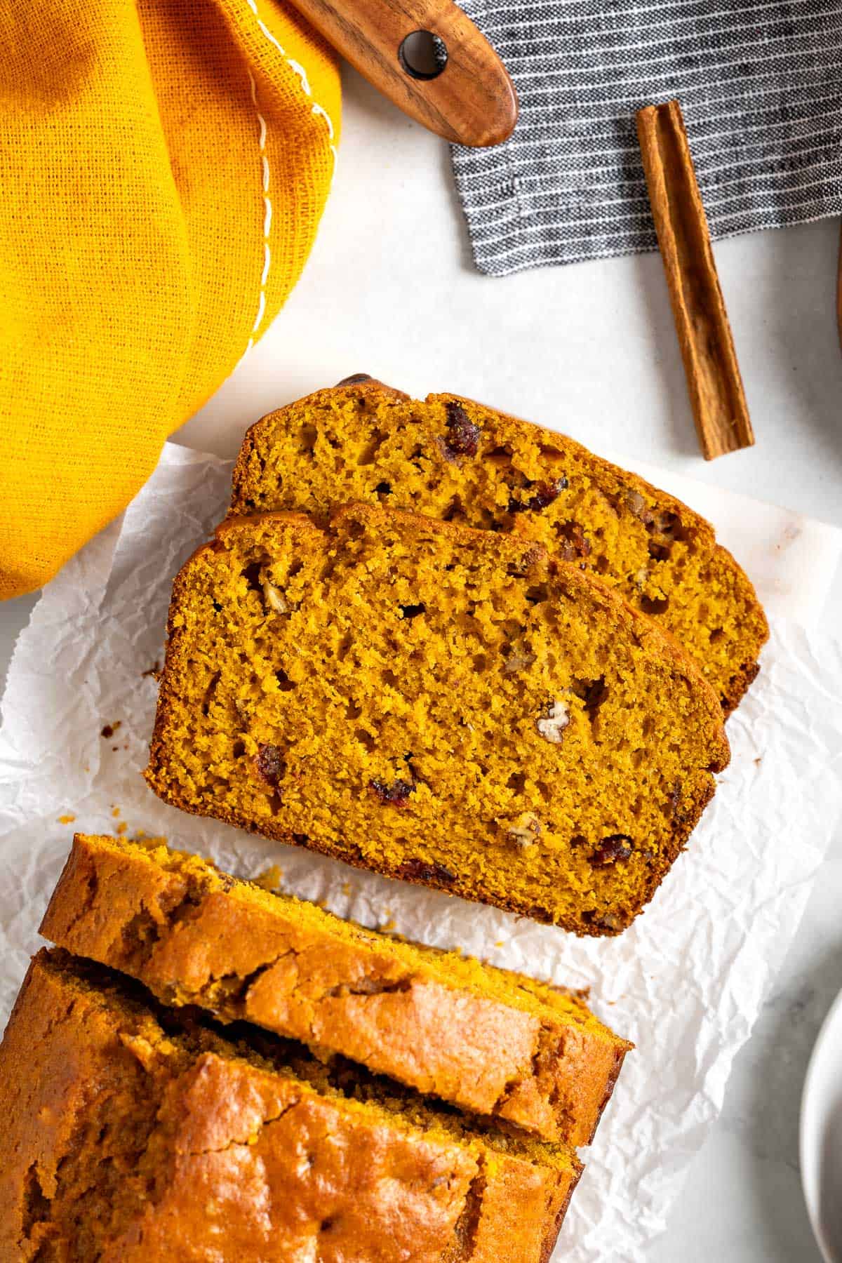 Two slices of pumpkin bread laying next to the whole loaf.