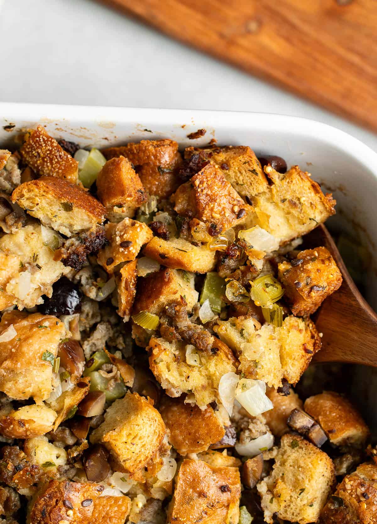 A wooden serving utensil scooping out a corner of the stuffing.