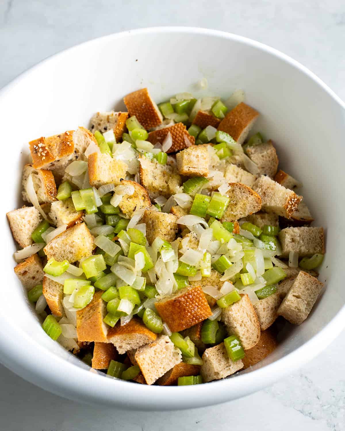 Bread cubes, and sautéed vegetables in a large mixing bowl.