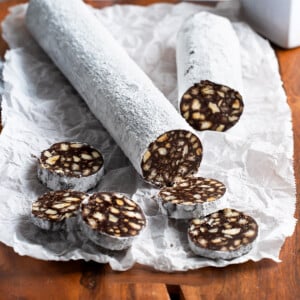 A partially-sliced chocolate salami on a wooden board.