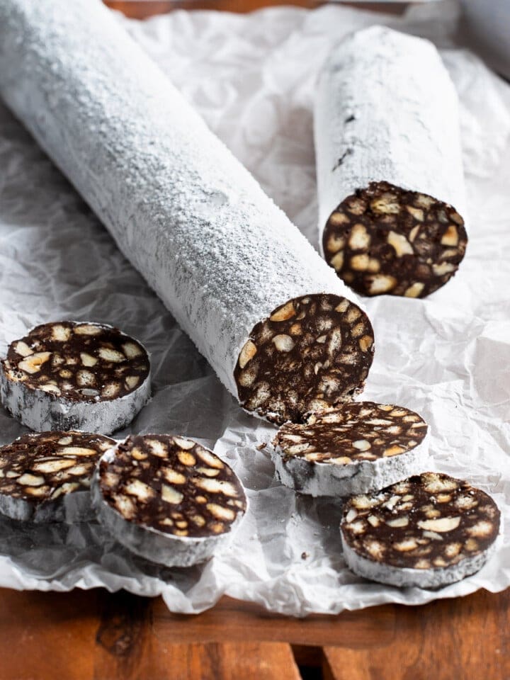 A partially-sliced chocolate salami on a wooden board.