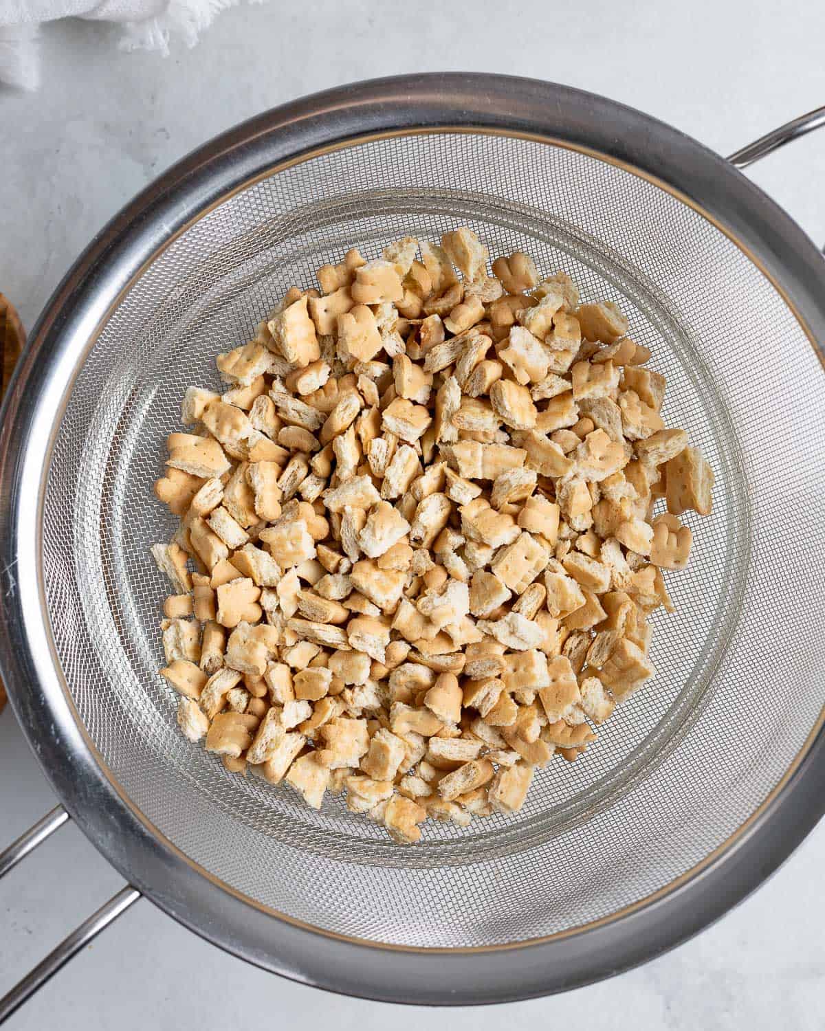 Chopped tea biscuit pieces in a large sieve to shake out the dust.