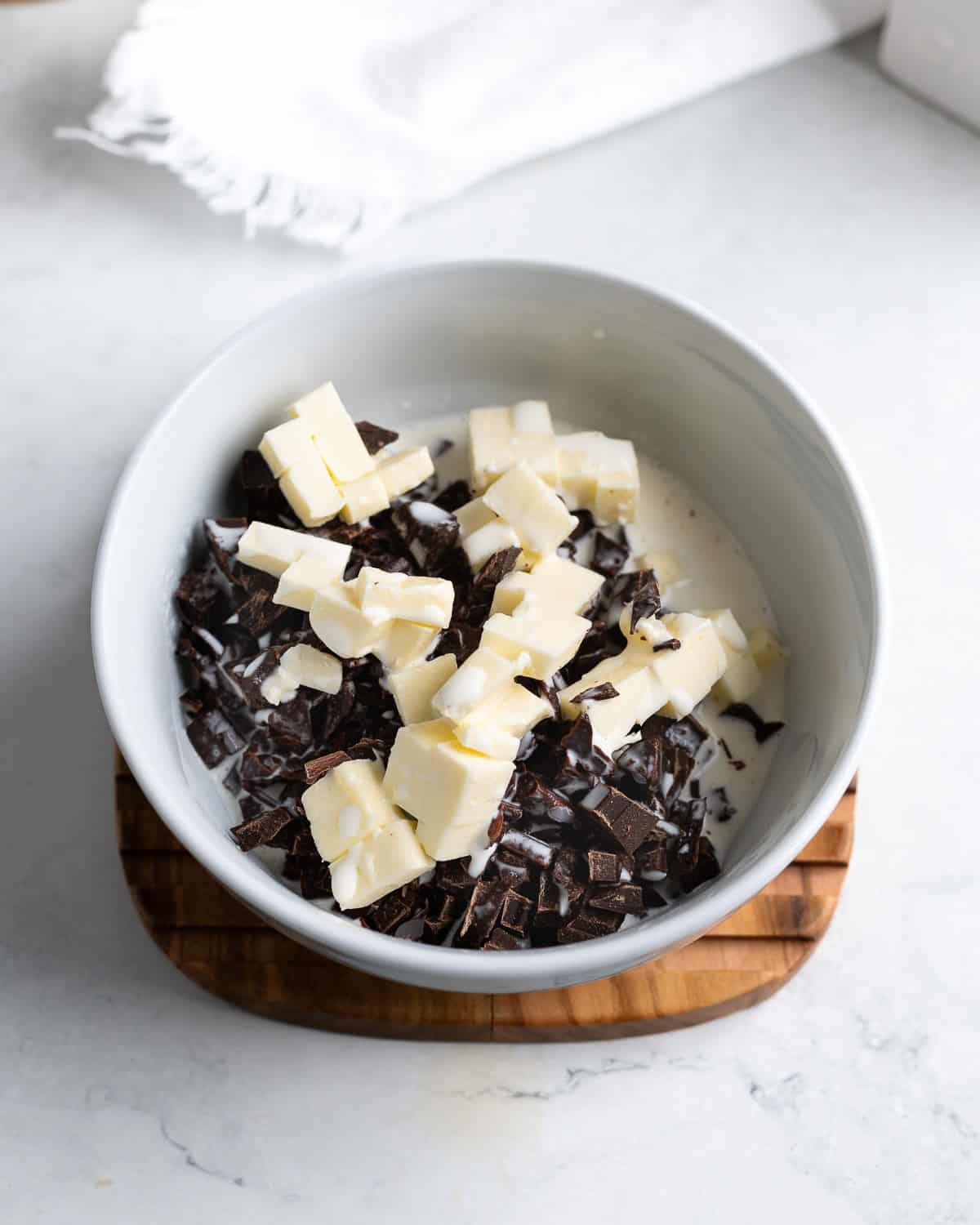 Cubed butter, chocolate, and cream in a bowl before being heated.