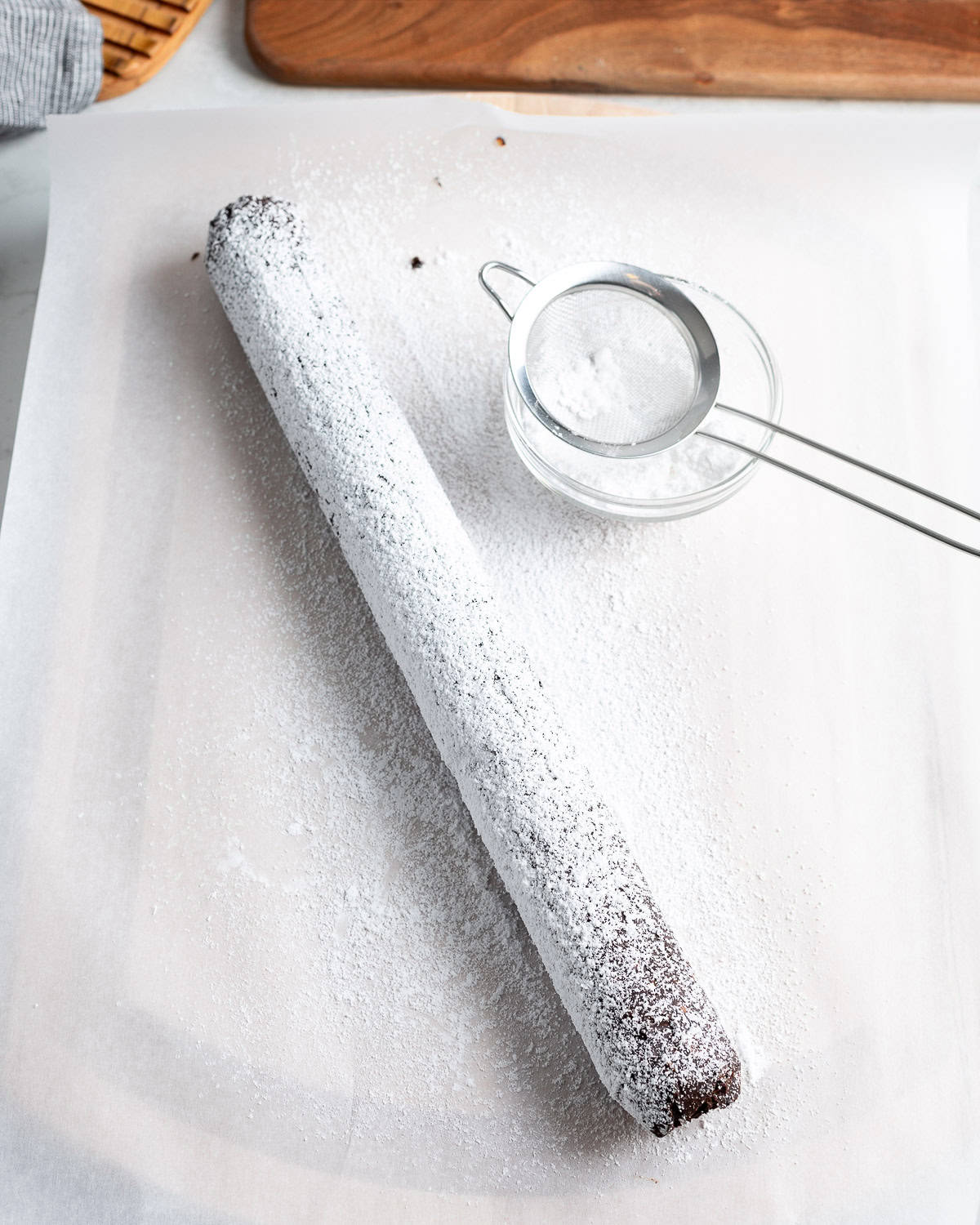 Powdered sugar being applied to the chocolate salami.