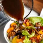 Dark colored maple balsamic vinaigrette being poured onto a side salad.