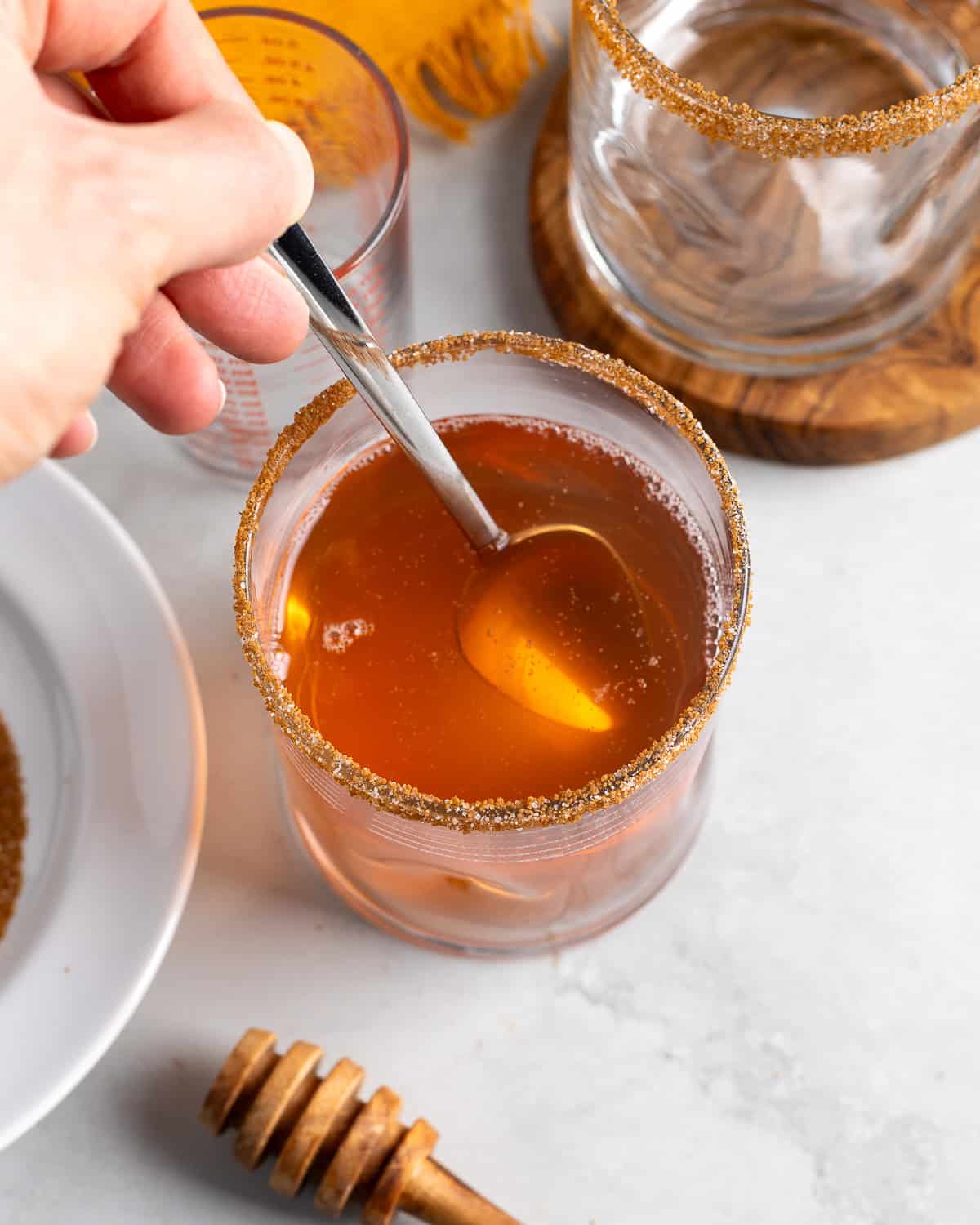 A hand stirring the drink ingredients in the glass.