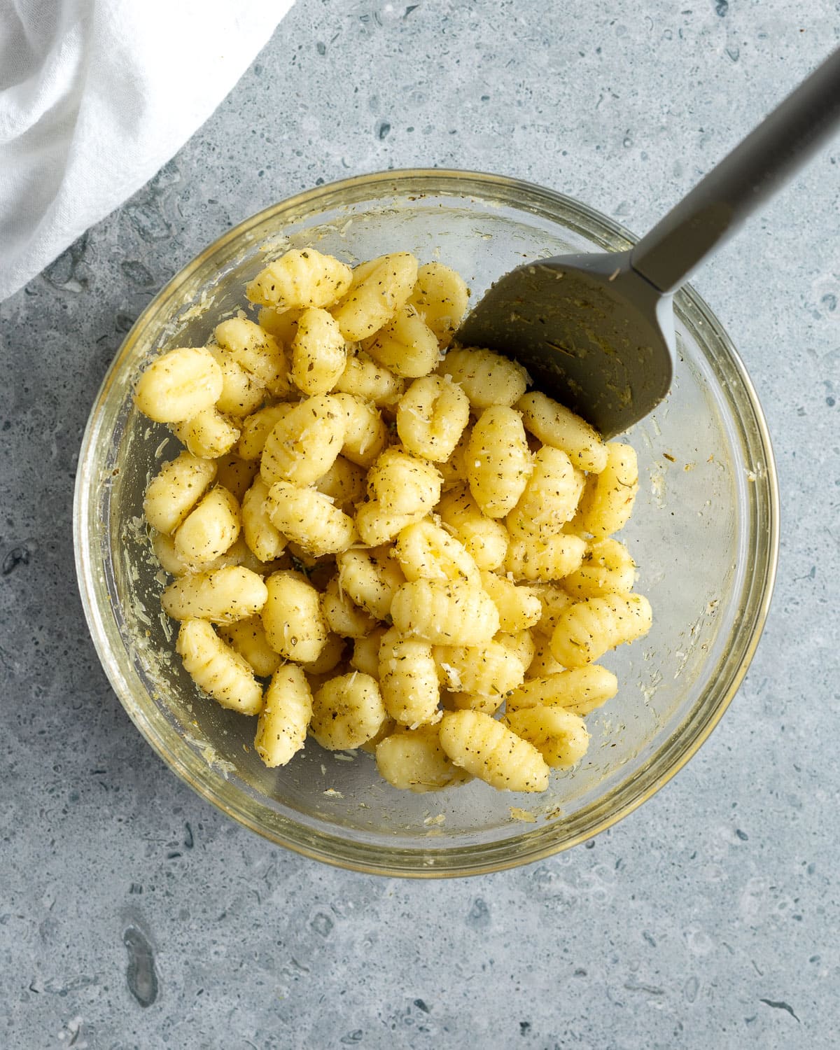 Gnocchi in a bowl coated with olive oil and spices.