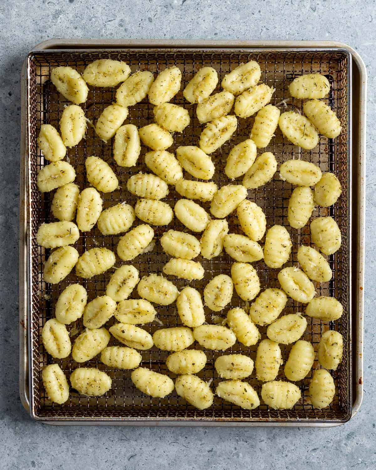 Gnocchi poured out onto an air fryer tray before being cooked.