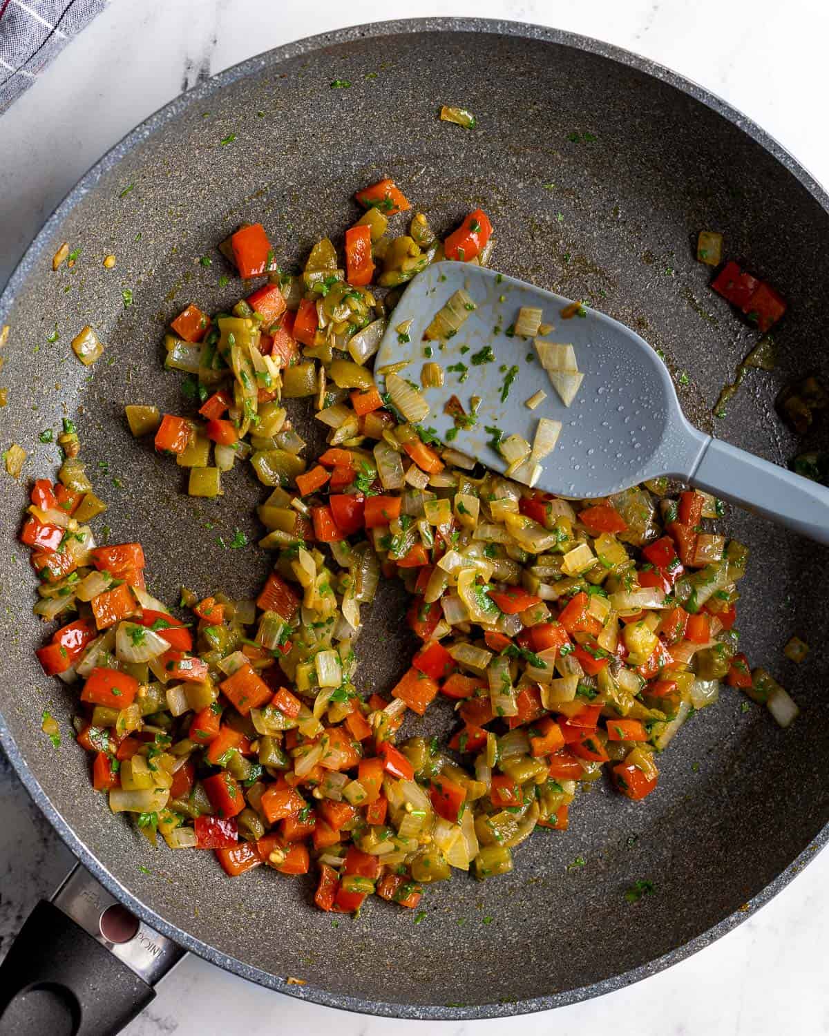 Sautéed pepper, onion, garlic, and chiles in a pan.