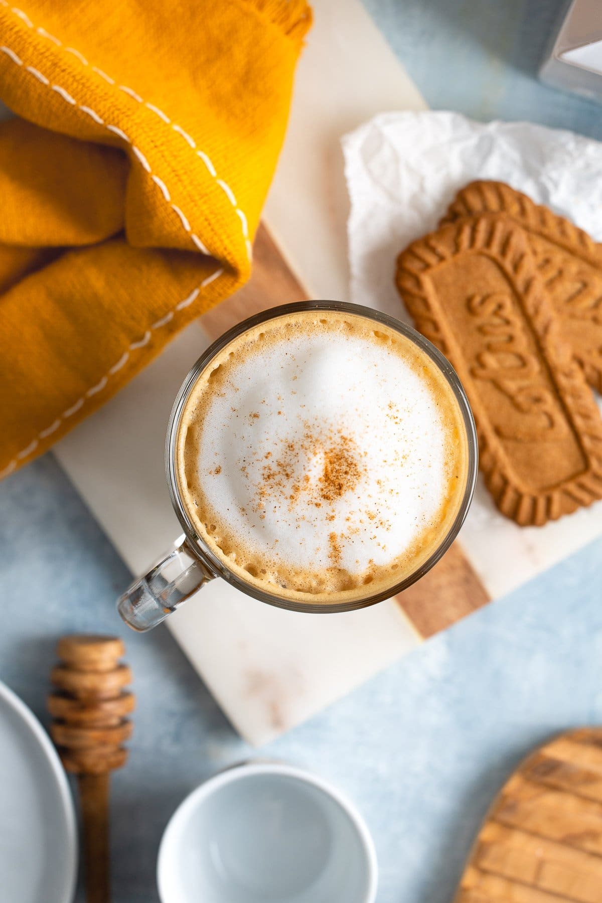A cookie butter latte next to two Biscoff cookies.