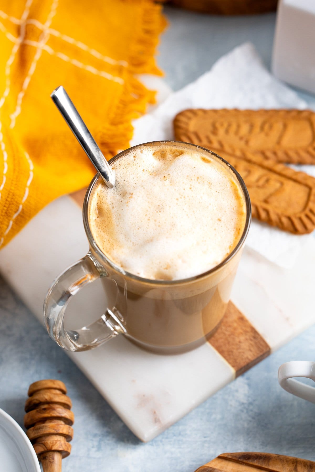 A spoon in the latte having stirred up the milk.