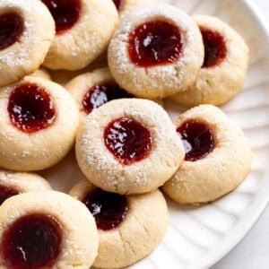 A platter of raspberry thumbprint cookies dusted with powdered sugar.