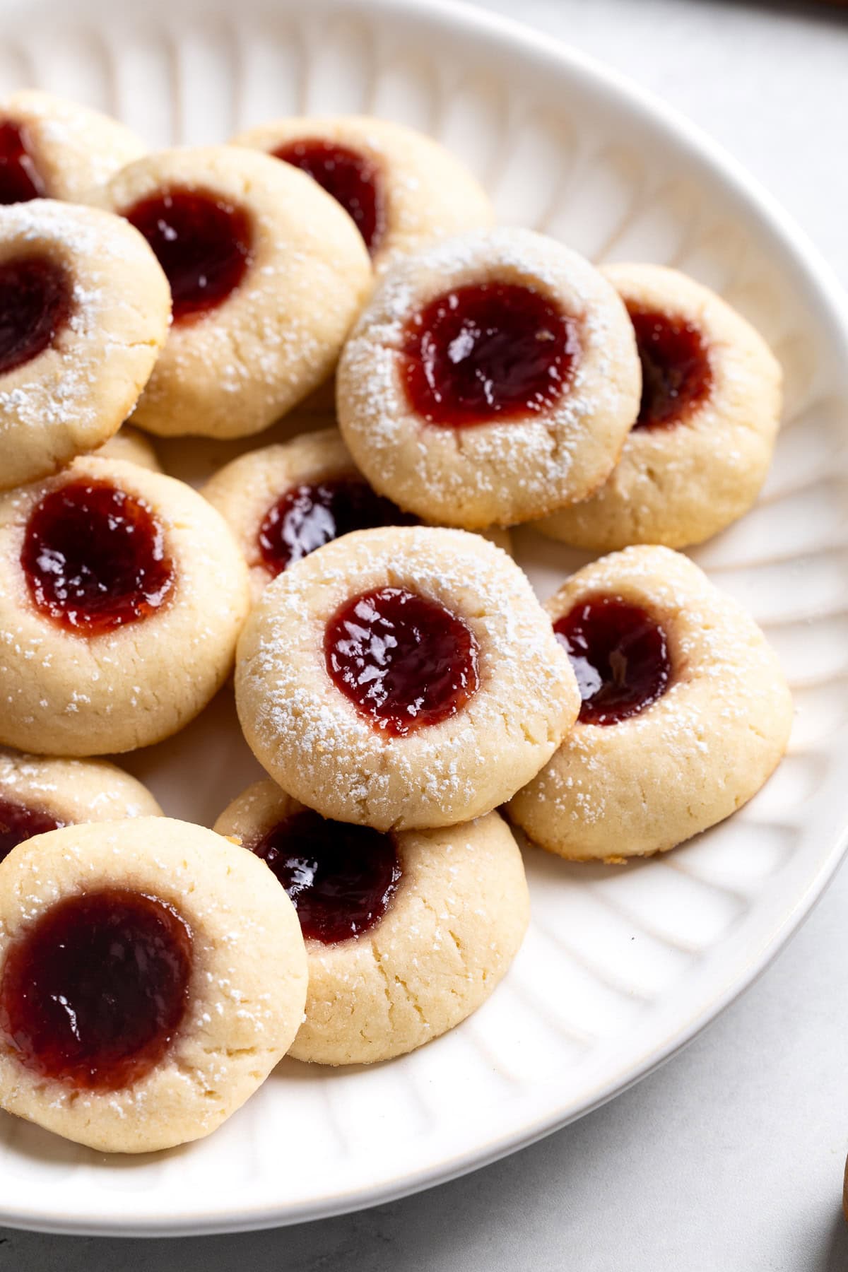 A platter of raspberry thumbprint cookies dusted with powdered sugar.