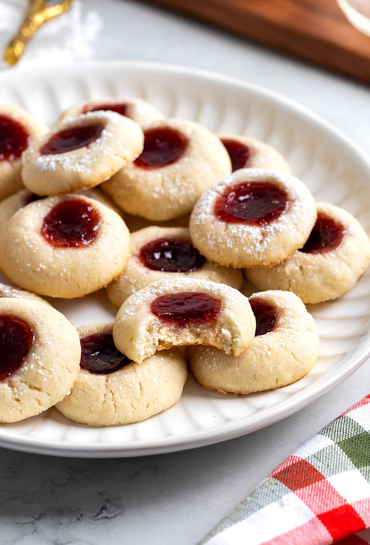 Thumbprint cookies on a plate with a bite taken out of one.