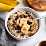 A bowl of stovetop steel cut oats topped with banana slices, pecans, and wild blueberries.