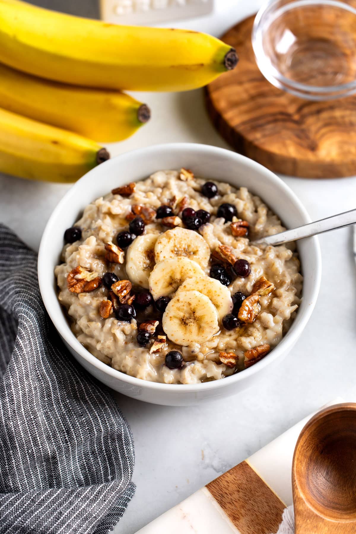 A bowl of stovetop steel cut oats topped with banana slices, pecans, and wild blueberries.