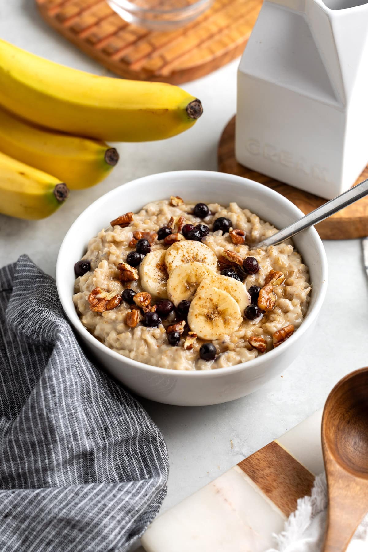 A bowl of stovetop steel cut oats topped with banana slices, pecans, and wild blueberries.