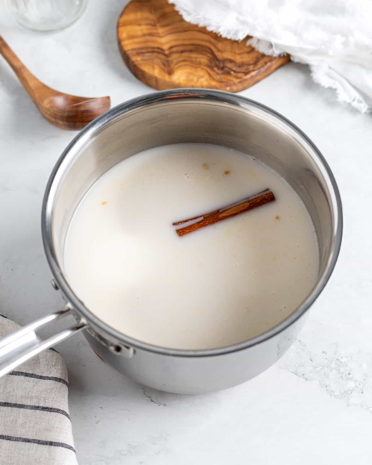 Water, milk, and a cinnamon stick added to the pot of toasted oats.
