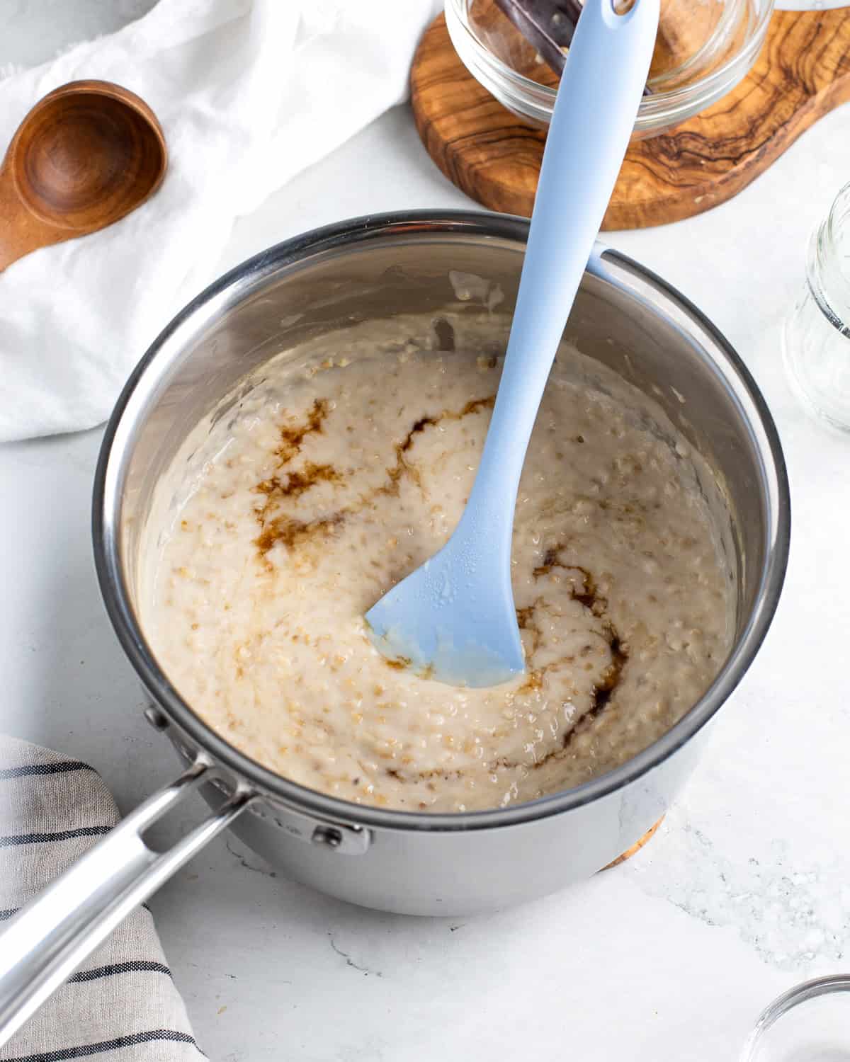 Maple syrup and brown sugar being stirred into the creamy oats.