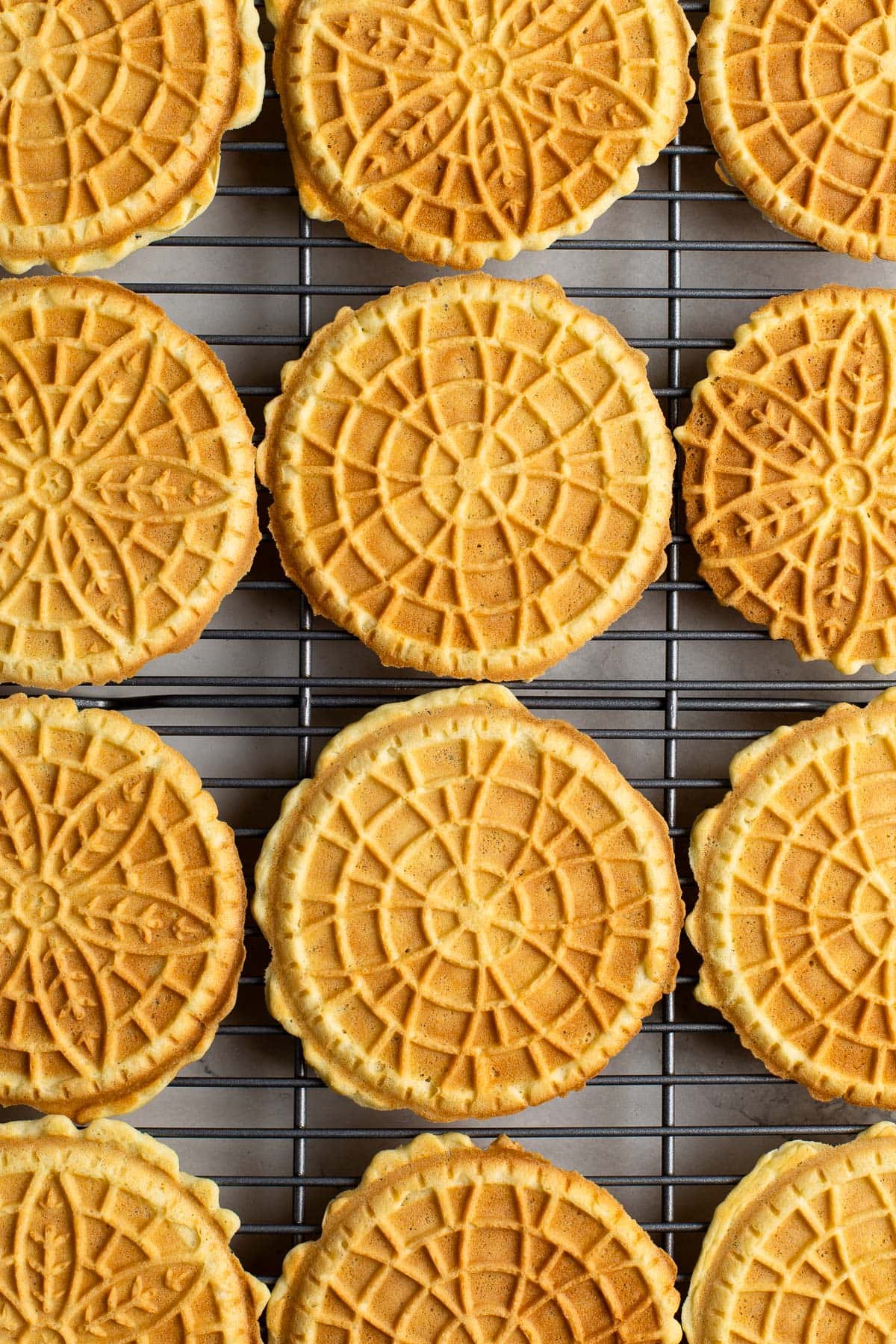 Pizzelle cookies cooling on a wire rack.