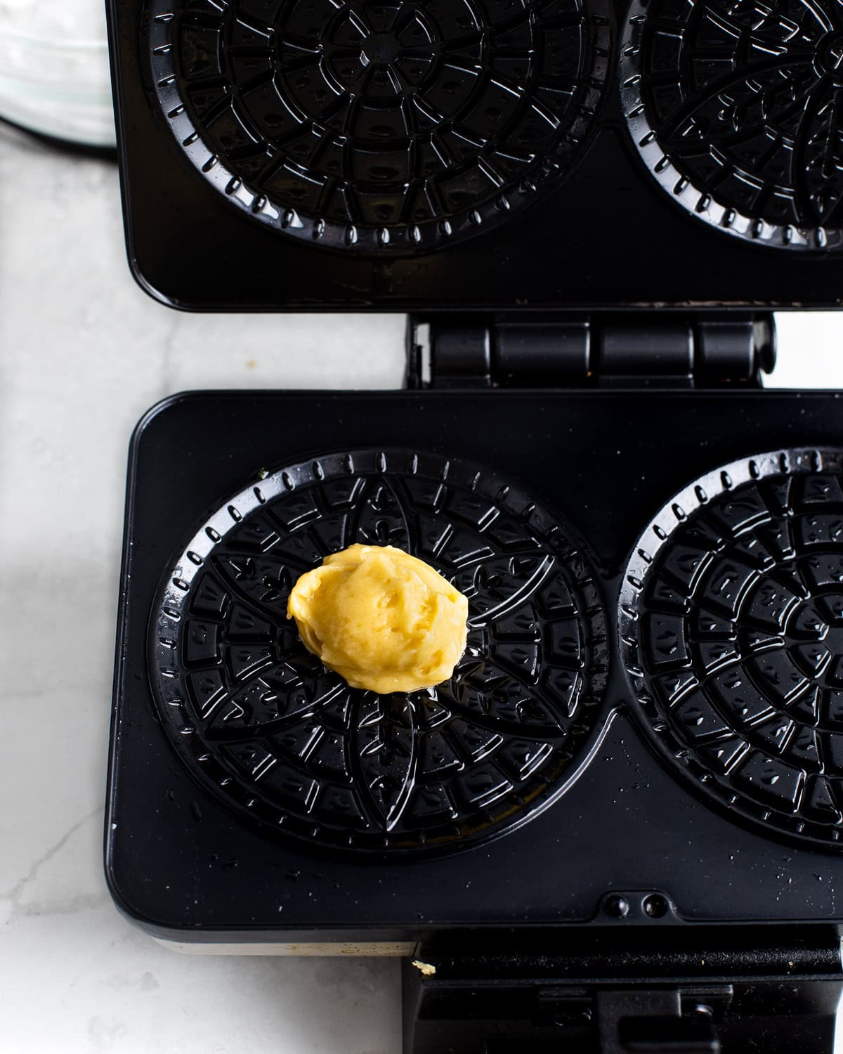 A dollop of batter on a hot pizzelle press before cooking.