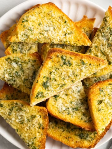 Wedges of sliced onion garlic bread on a plate to serve.