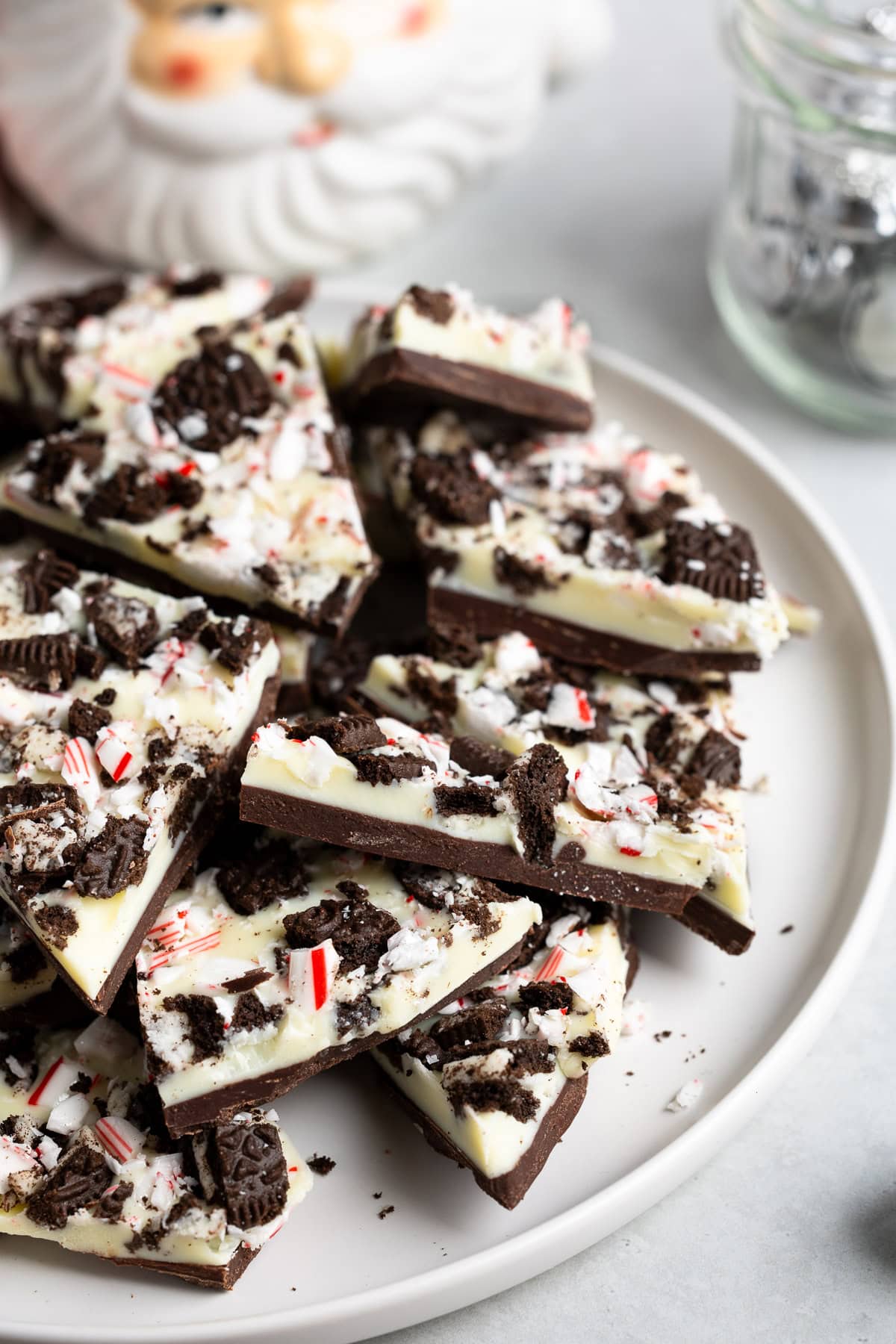 Pieces of Oreo peppermint bark on a plate next to a Santa mug.