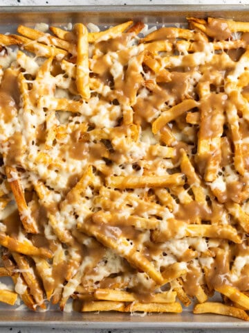Gravy smothered disco fries on a sheet pan.