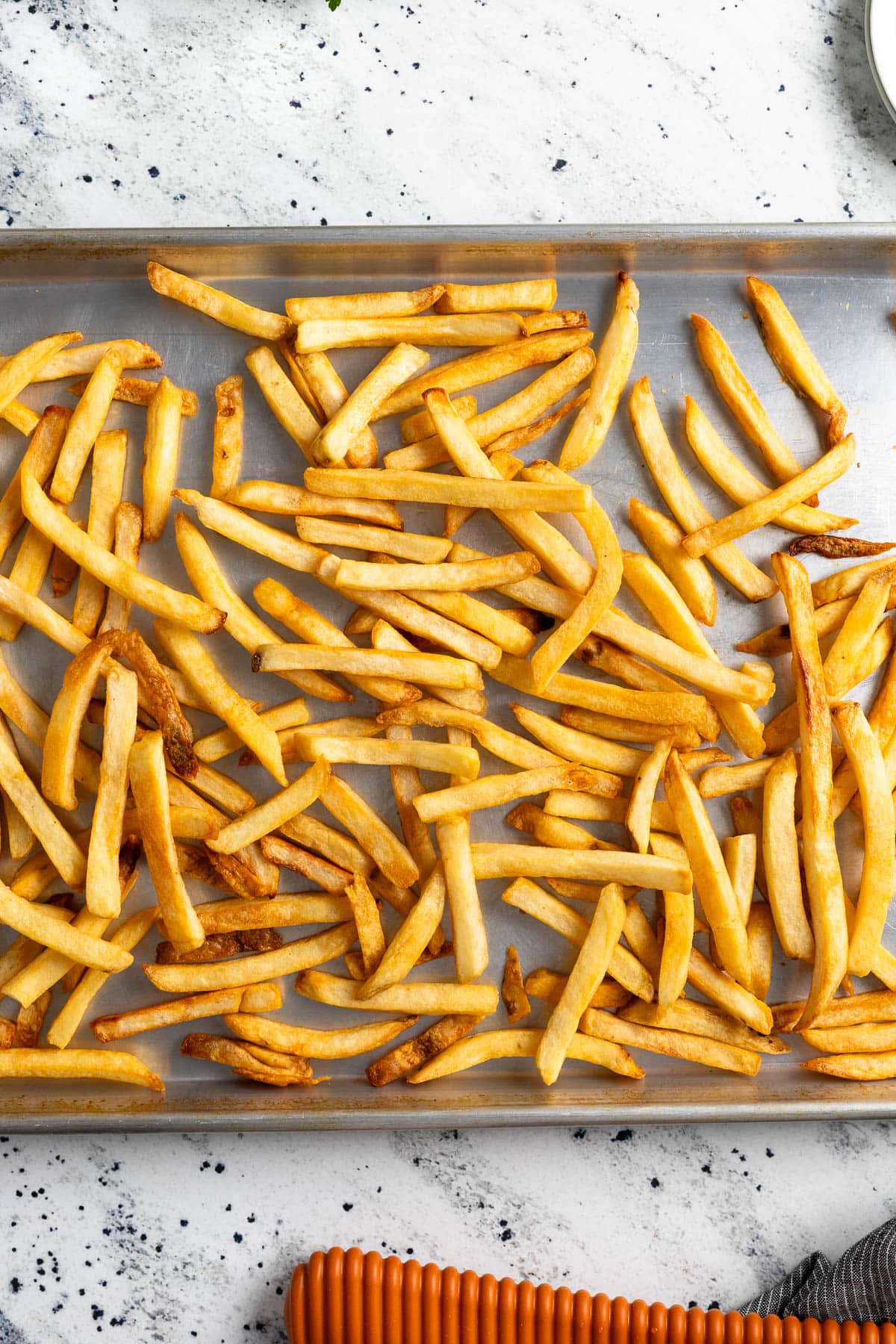 Extra crisp French fries scattered on a big rimmed pan.