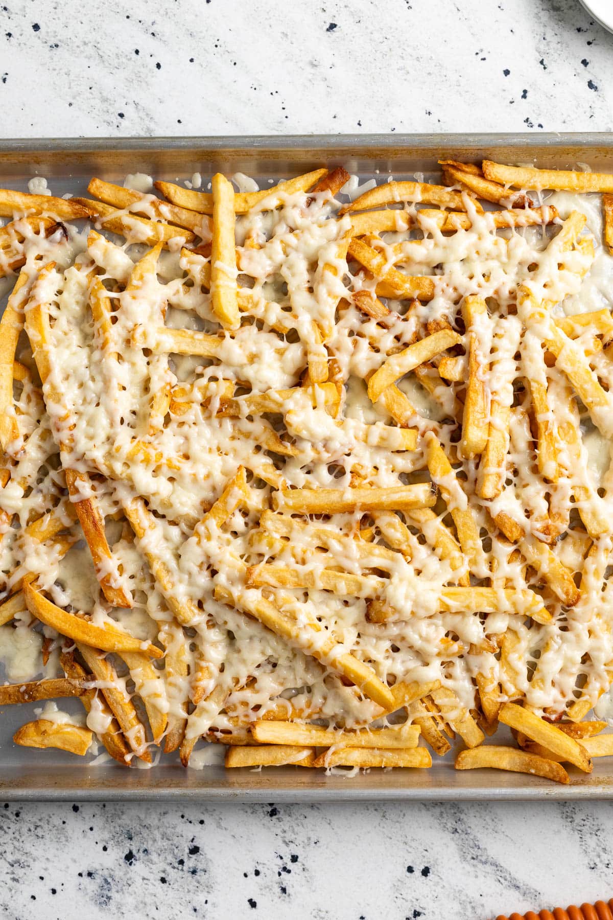 Shredded mozzarella cheese melted on top of French fries.